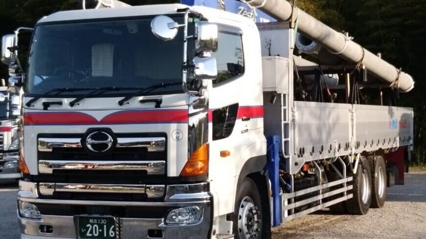 コンクリートポールを積載した橋村運送のユニック車（クレーン付平ボディ車）