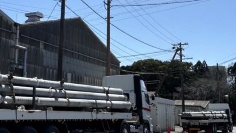 出荷ヤードでコンクリートポールを積載した平ボディ車